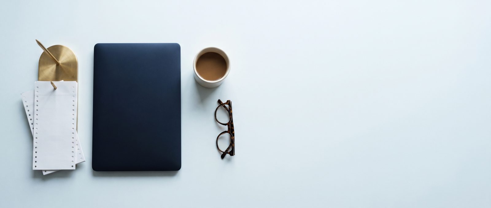 A desk with a spike of paper dockets, a closed laptop and a cup of coffee