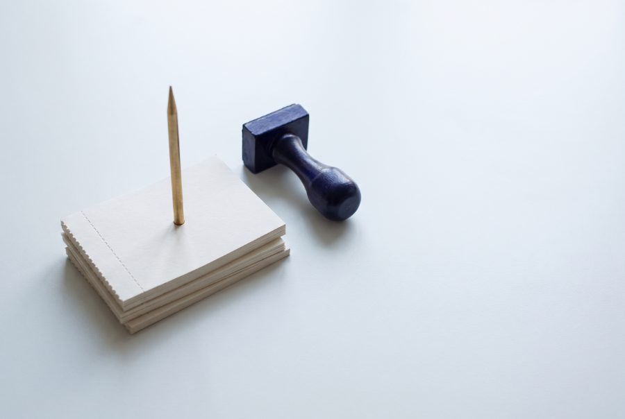 A brass spike holding a stack of blank dockets beside an indigo stamp